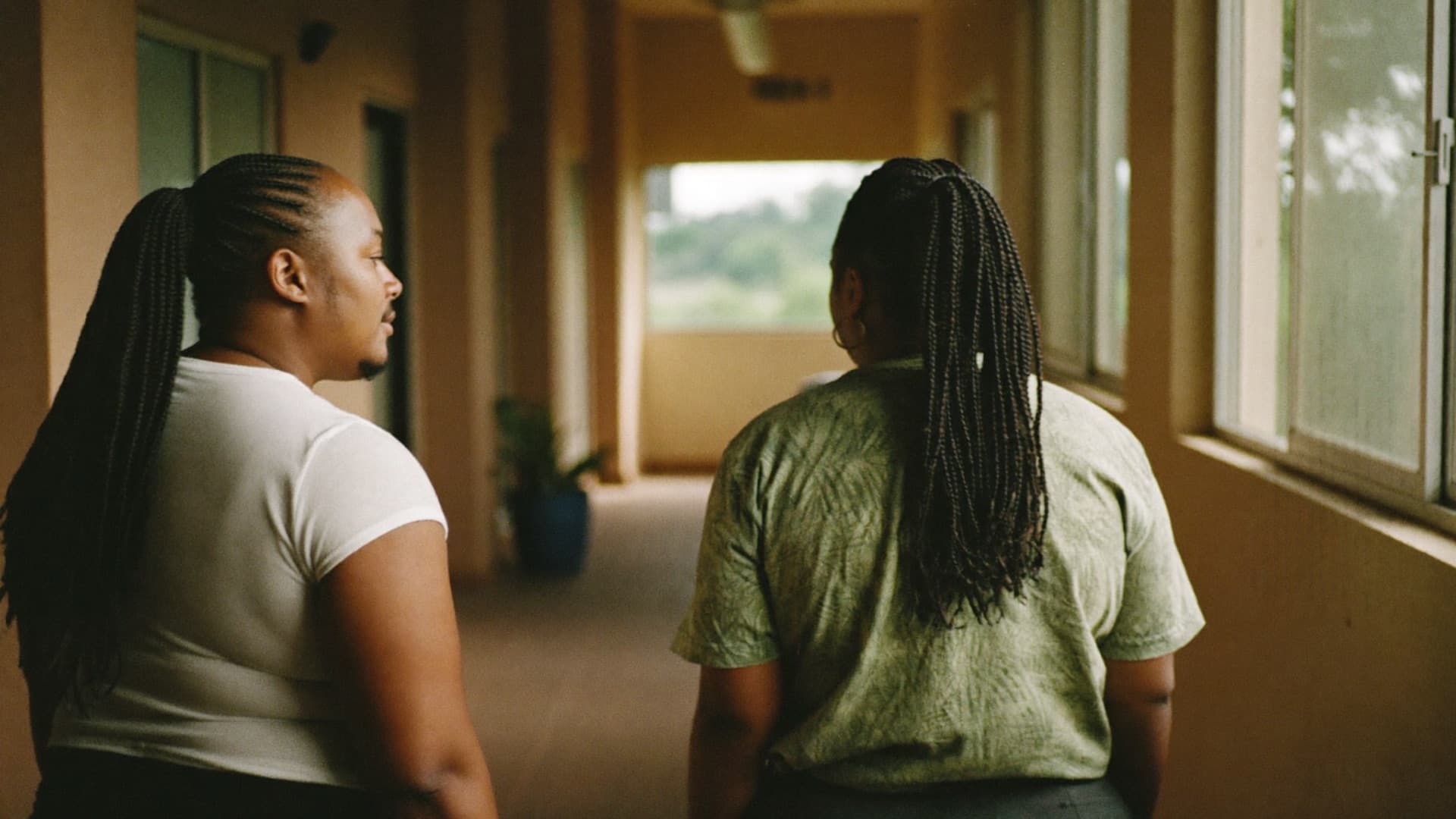 Two colleagues talking as they walk along a sunlit corridor